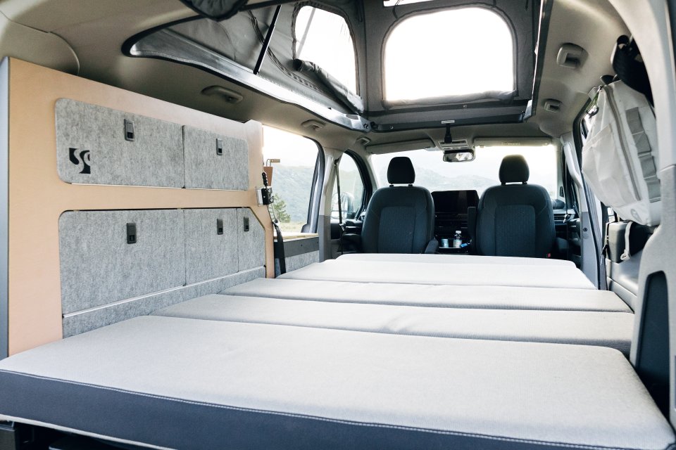 Innenansicht vom Ford Tourneo Custom Camper beim Camping mit Heckschrank und Bett