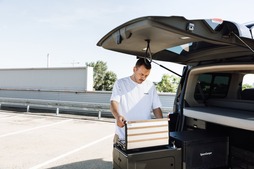 Person am VW Camper Heck mit Hand an modularer Camping Küche von SpaceCamper